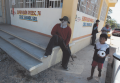 A boy walks past a member of the unofficial “community police” in Cruz Grande, Guerrero, Mexico.