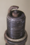 A worn spark plug showing fuel  and/or oil deposits.