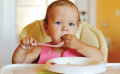 6 month old baby in highchair eating
