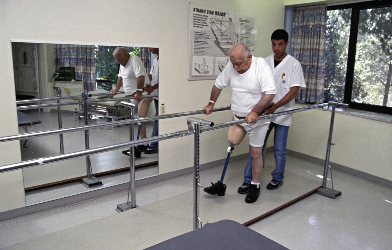  A therapist assisting an amputee patient to regain mobility and strength after amputation. 