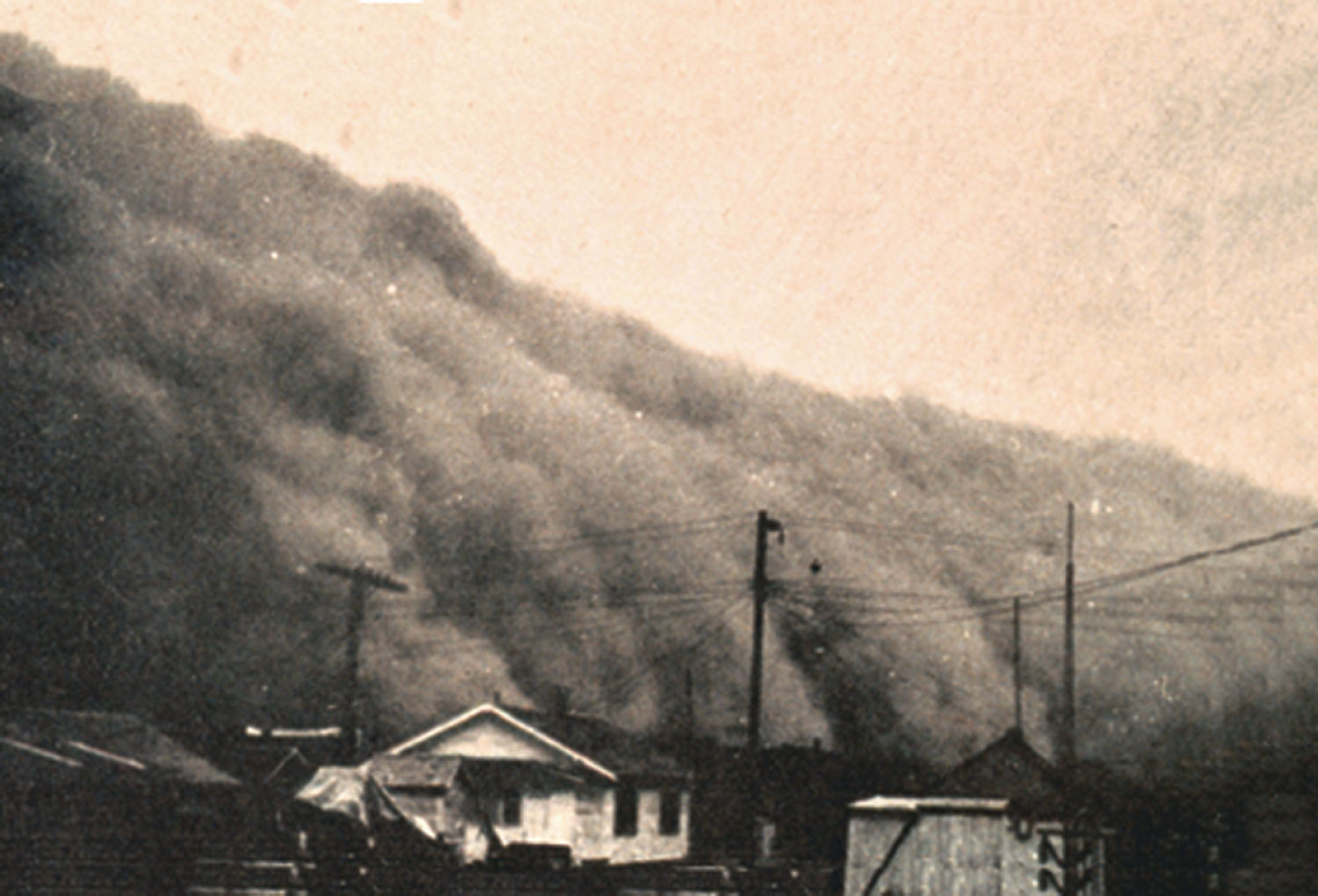 A giant dust cloud about to descend on a farm in Kansas during the 1930s