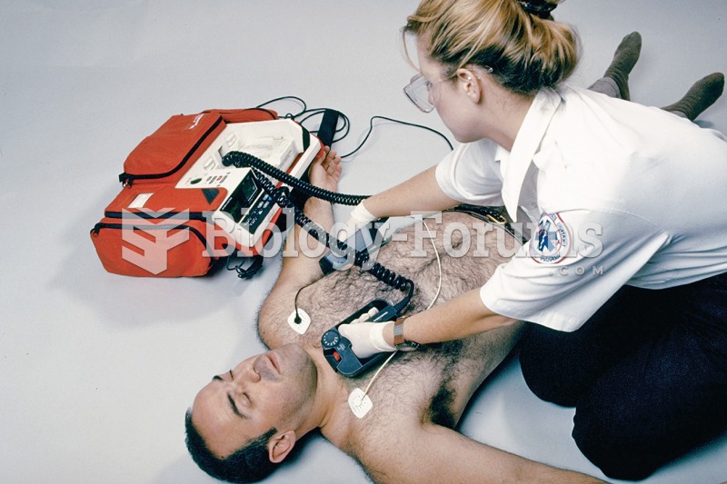 An emergency medical technician positions defibrillator paddles on the chest of a supine male patien