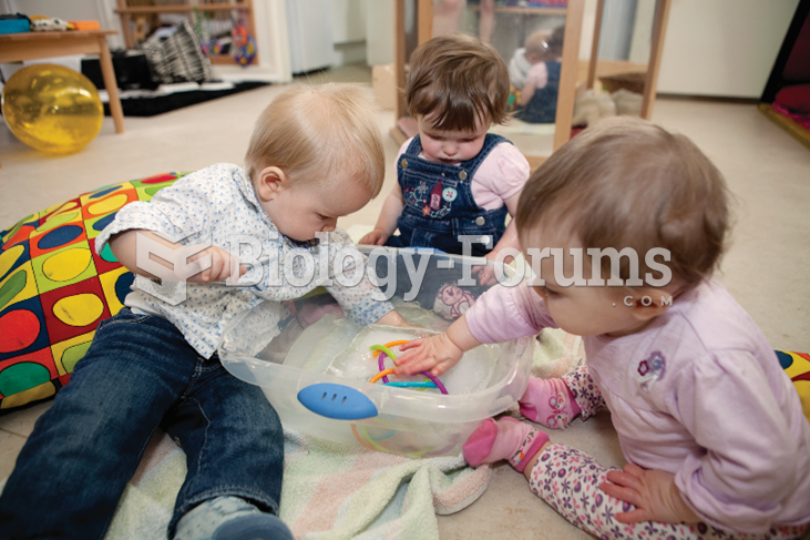 Three toddlers sit on the floor playing with a toy. 